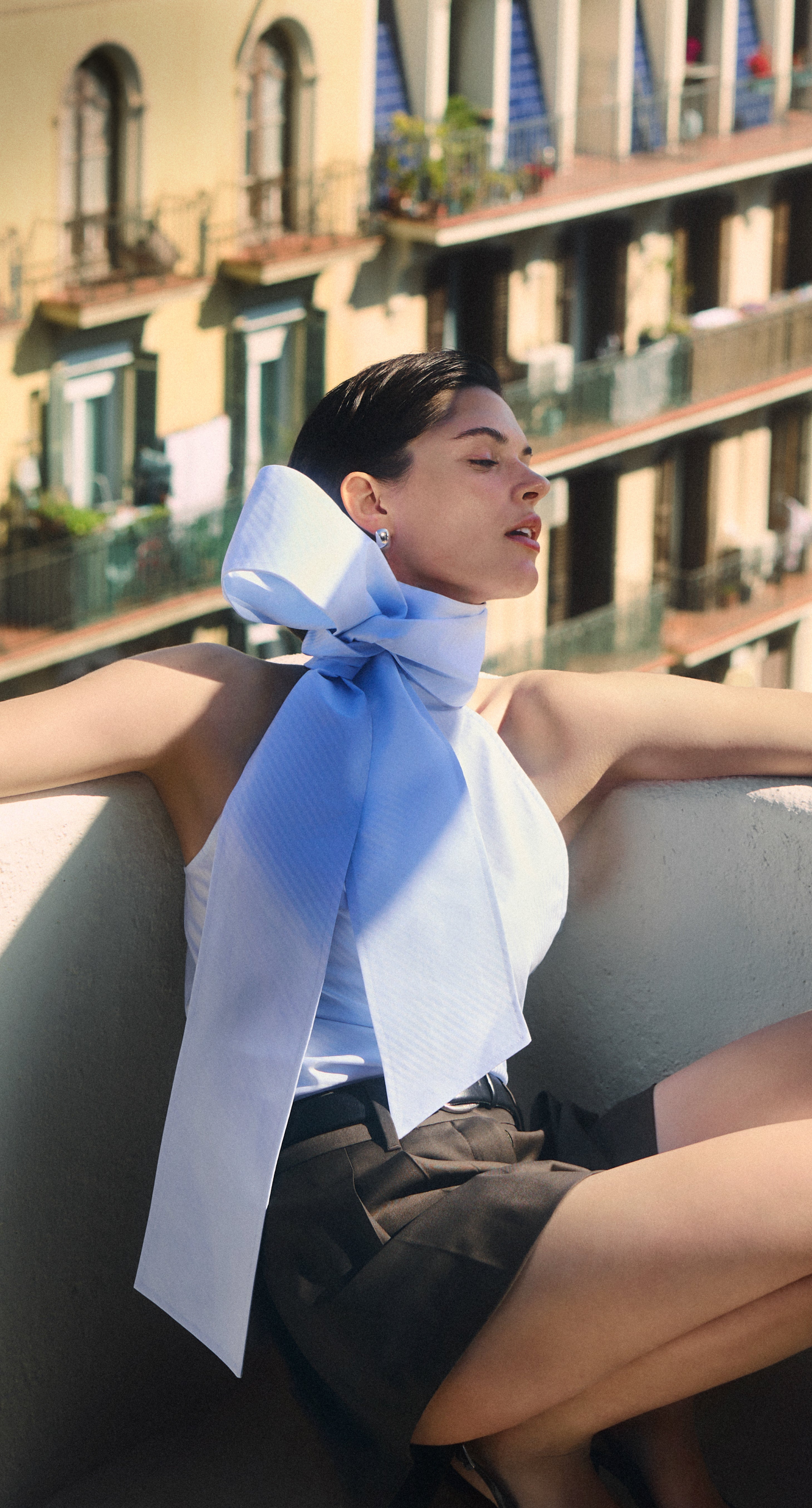 Woman with a blue and white scarf sitting on a boat with a scenic background